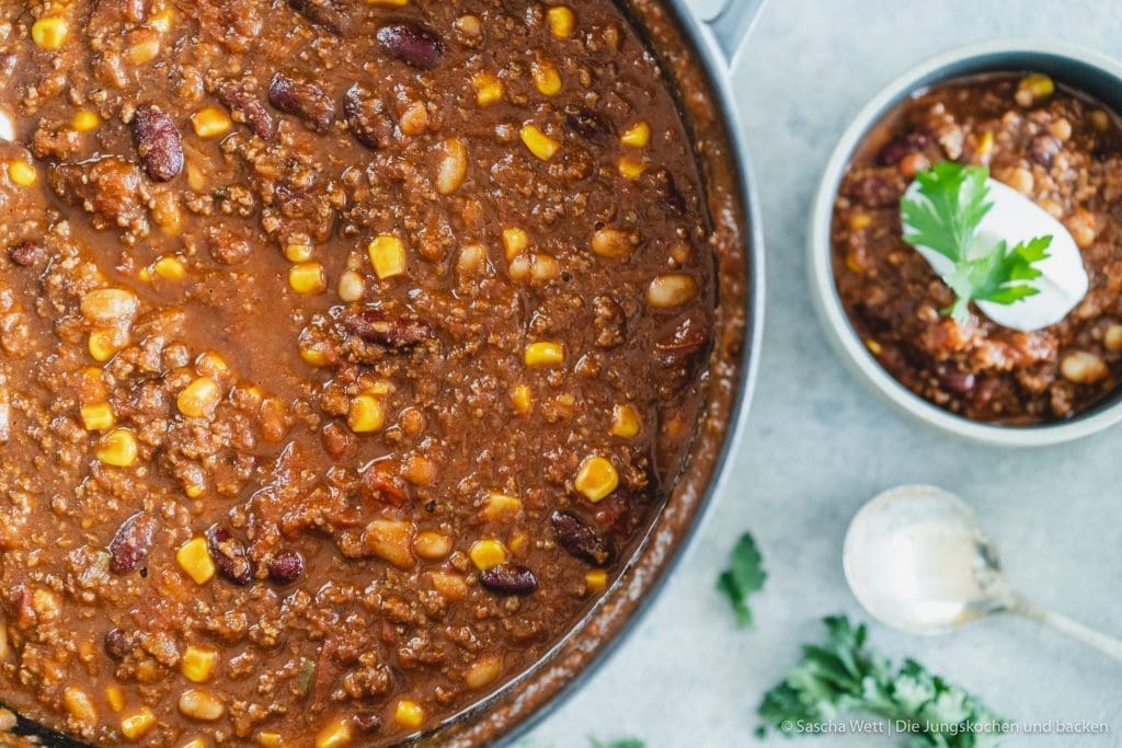 Chili con carne 5 Chili Con Carne 5 | Torsten und ich haben Anfang des Monats unsere Geburtstage nachgefeiert. Da wir aber nur ein paar Tage vorher aus dem Urlaub zurückgekommen sind, war nicht wirklich viel Zeit für riesige Vorbereitungen. Daher haben wir auf einen Partyfood-Klassiker schlechthin zurückgegriffen - ein leckeres Chili con carne! Denn ein geniales Chili lässt sich in riesigen Mengen und mit super wenig Vorbereitung zubereiten - eigentlich macht es sich fast von alleine. Trotzdem hat wahrscheinlich jeder ein etwas anderes Rezept für sein Chili con carne zur Hand. In unsere Version kommen 1-2, für unsere Freunde, unwahrscheinlichen Zutaten, aber genau die machen es aus.