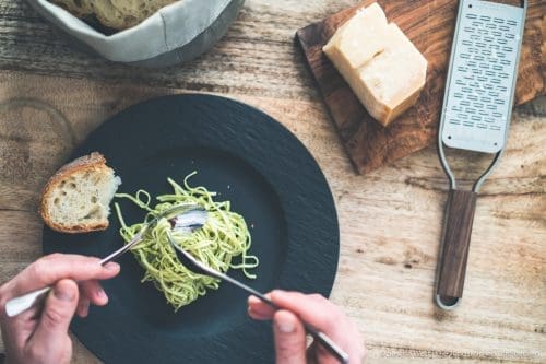 Spaghetti auf Teller. Spaghetti werden mit Gabel und Löffel aufgerollt