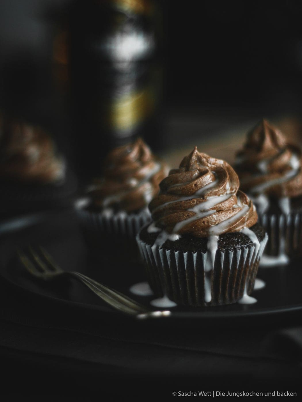Cupcakes auf Teller mit Flasche im Hintergrund