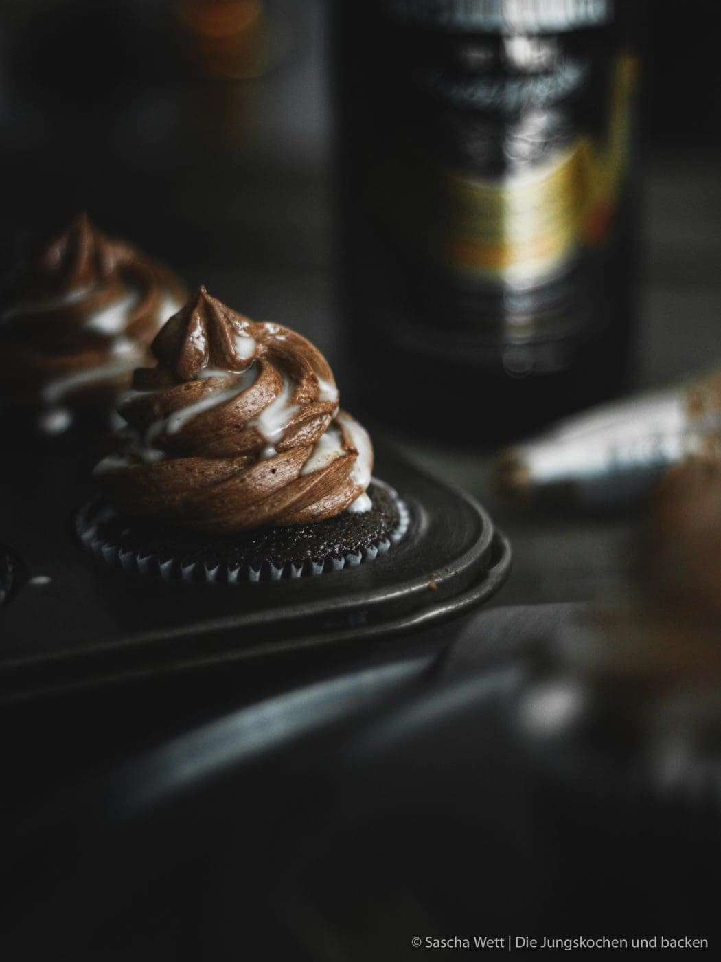 Cupcakes auf Teller mit Flasche im Hintergrund