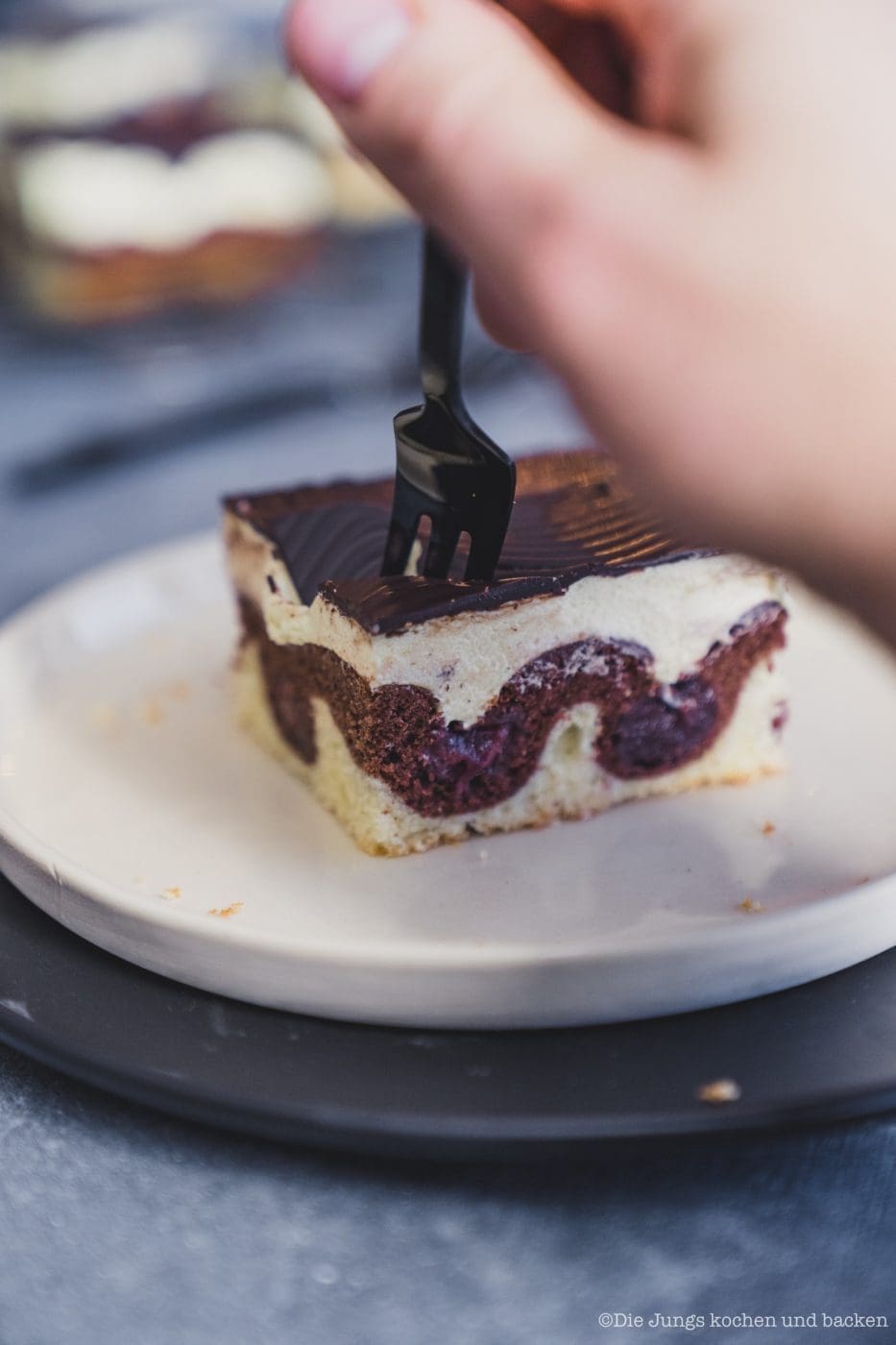 Donauwelle 2020 4 | Bei mir zu Hause heißt dieser Kuchen einfach „Monis Donauwelle“ nach meiner Mama. Der kommt immer auf den Geburtstagstisch ... saftig, süß, mit Schattenmorellen, Vanille-Puddingcreme und Schokoguss mit diesen markanten Wellen. Klingt nach ganz viel Aufwand? Keine Sorge mit etwas Planung und den richtigen Kniffen gelingt der Klassiker total entspannt. Ich verrate dir, wie du Pudding und Butter schön langsam vereinst, damit die Creme nicht gerinnt, und wie du den Schokoguss wackelig-dekorativ hinbekommst. Mehr Familienliebe auf dem Blech geht nicht.