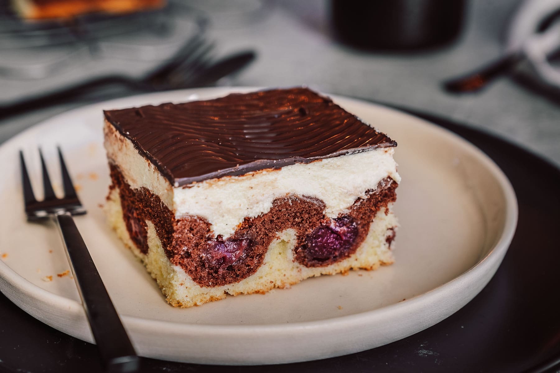 Mama Donauwelle 3 | Bei mir zu Hause heißt dieser Kuchen einfach „Monis Donauwelle“ nach meiner Mama. Der kommt immer auf den Geburtstagstisch ... saftig, süß, mit Schattenmorellen, Vanille-Puddingcreme und Schokoguss mit diesen markanten Wellen. Klingt nach ganz viel Aufwand? Keine Sorge mit etwas Planung und den richtigen Kniffen gelingt der Klassiker total entspannt. Ich verrate dir, wie du Pudding und Butter schön langsam vereinst, damit die Creme nicht gerinnt, und wie du den Schokoguss wackelig-dekorativ hinbekommst. Mehr Familienliebe auf dem Blech geht nicht.