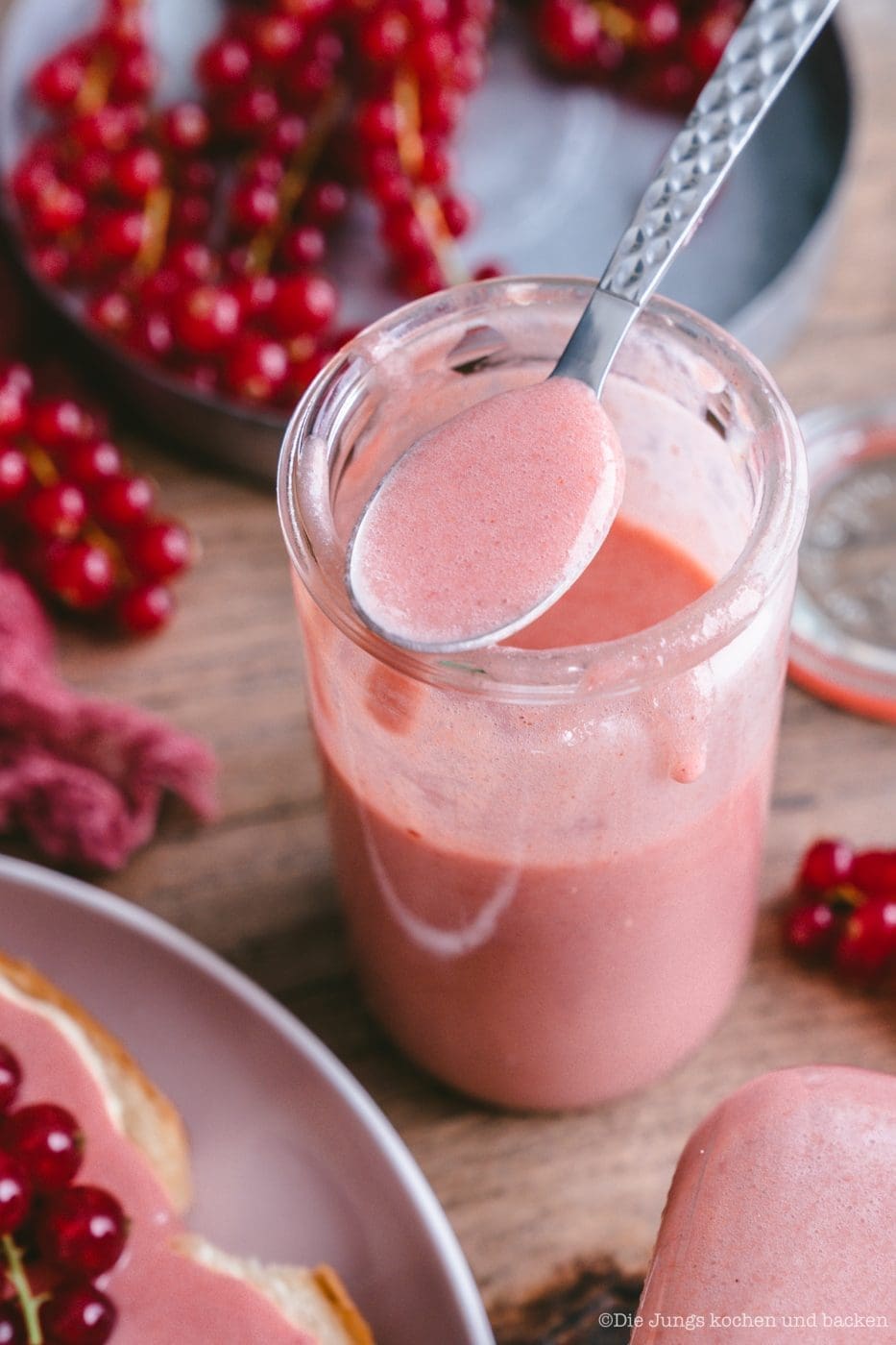 Glas Johannisbeer Curd mit einem Löffel voll cremigem Aufstrich