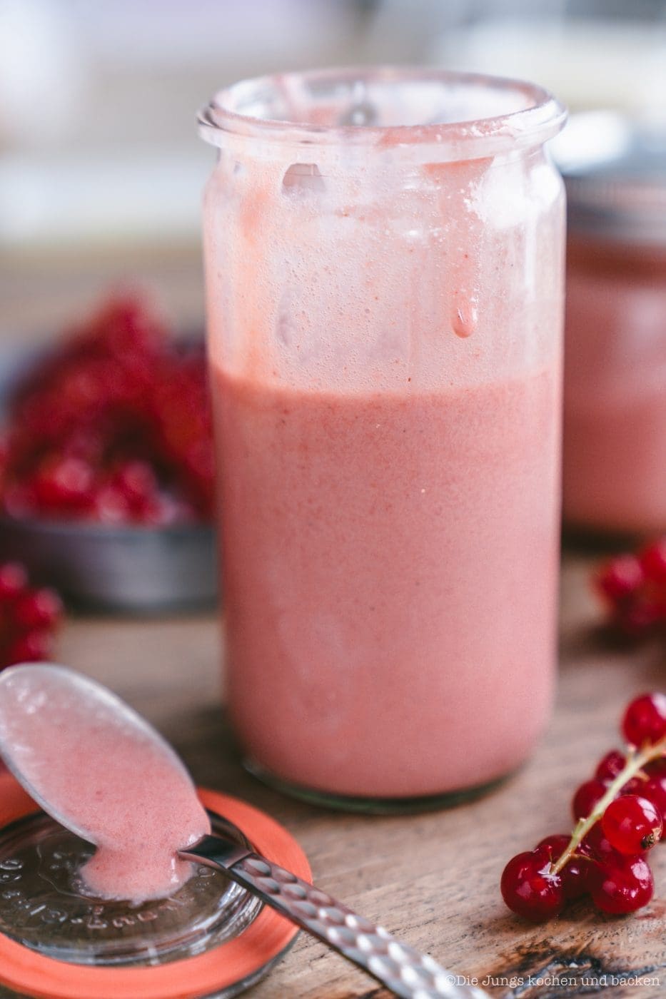 Johannisbeer Curd im Glas, daneben Löffel und frische Beeren