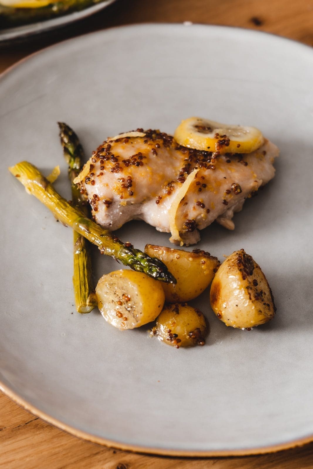 Angerichteter Teller mit Honig-Senf-Hähnchen vom Blech 