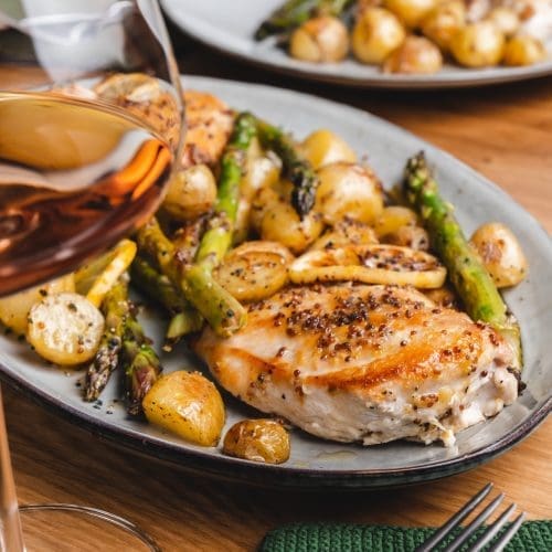 Honig-Senf-Hähnchen vom Blech auf dem Servierteller. Teller im Hintergrund