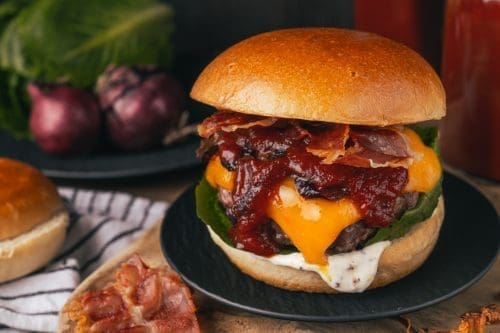 Klassischer BBQ-Cheeseburger mit dick Cheddar und Bacon 2 Rezept für einen klassischen BBQ-Cheeseburger, den wir mit einer dicken Scheibe Cheddar belegt haben. Getoppt von unserer BBQ-Sauce und Bacon, einfach perfekt.