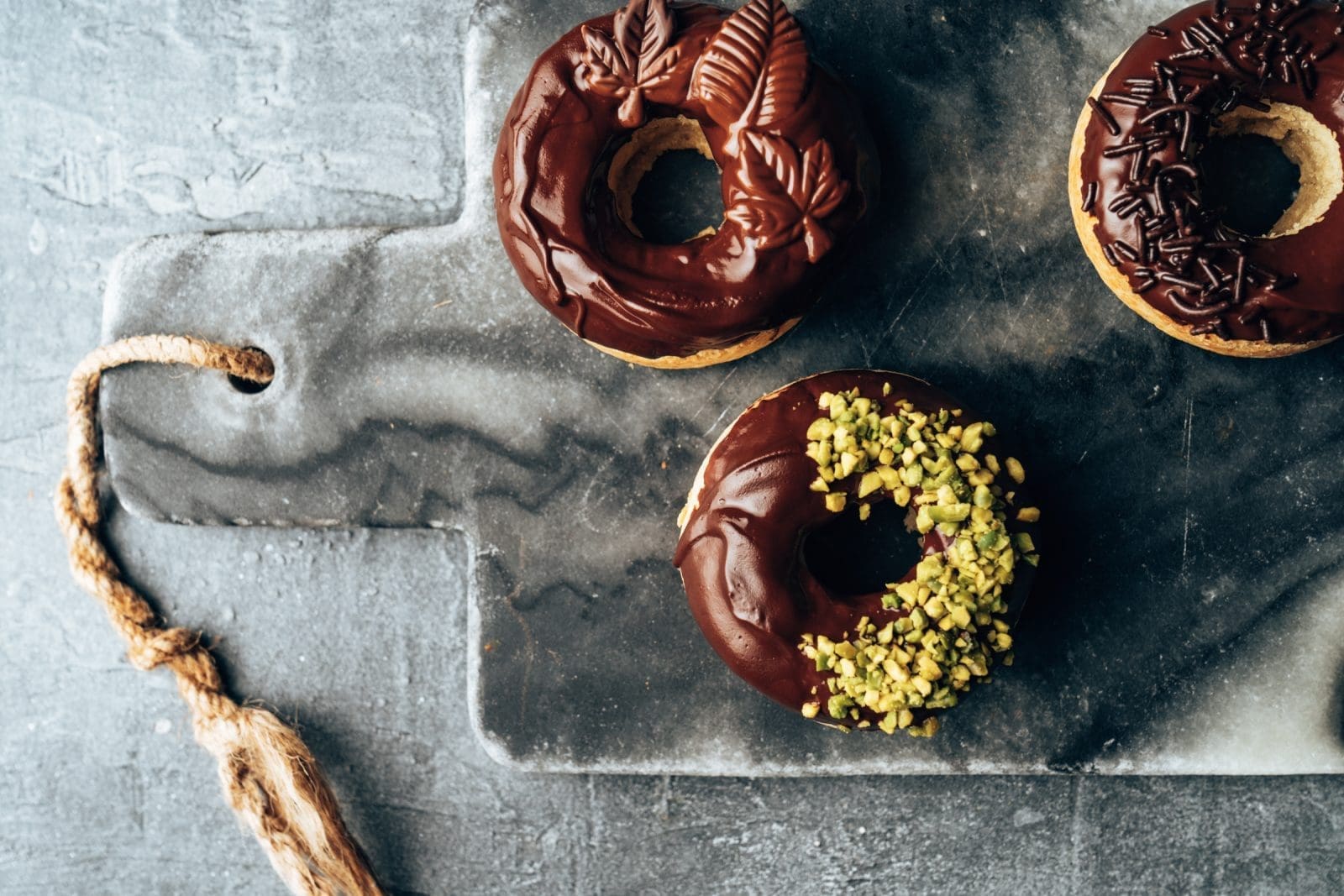 Vegane Schoko Donuts 5 | Wenn es Euch so geht wie uns, sind die einzigen veganen Donuts, die Ihr bisher kanntet, trocken und geschmacklos. Daher mussten wir uns einfach an einem eigenen veganen Rezept für saftige Donuts austesten! Wir probieren ja  ständig neue Rezepte aus und entdecken interessante Dinge im Supermarkt. Daher geht es heute auch um Schokoladenglasur - unsere Lieblingsglasur. Wir haben uns so richtig bei der Verzierung der veganen Donuts ausgetobt und sie waren ein solcher Erfolg, dass uns jetzt jeder nach diesem einfachen Rezept fragt.