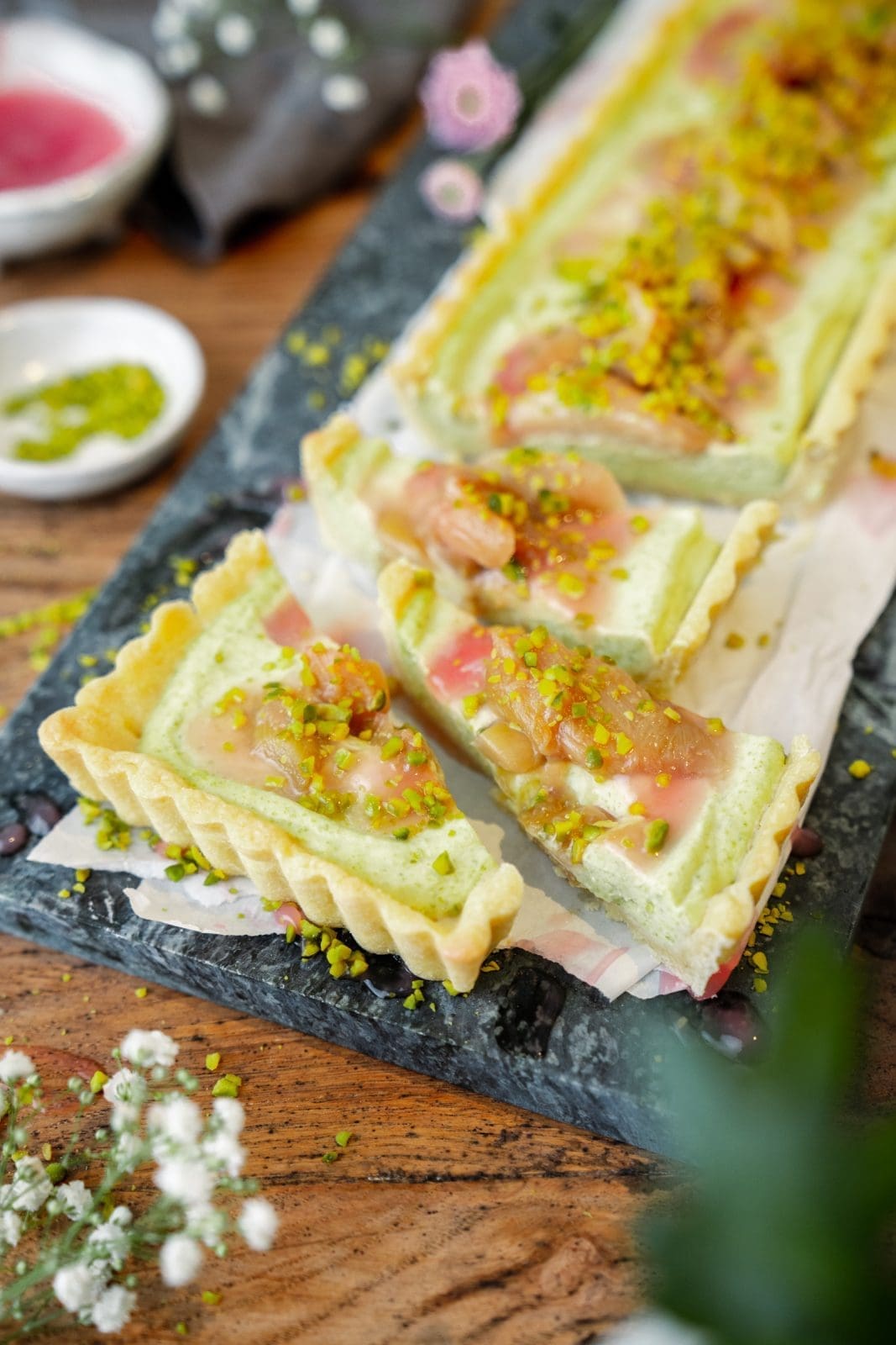 Pistazien-Tarte mit Rhabarber angeschnitten auf dem Tisch