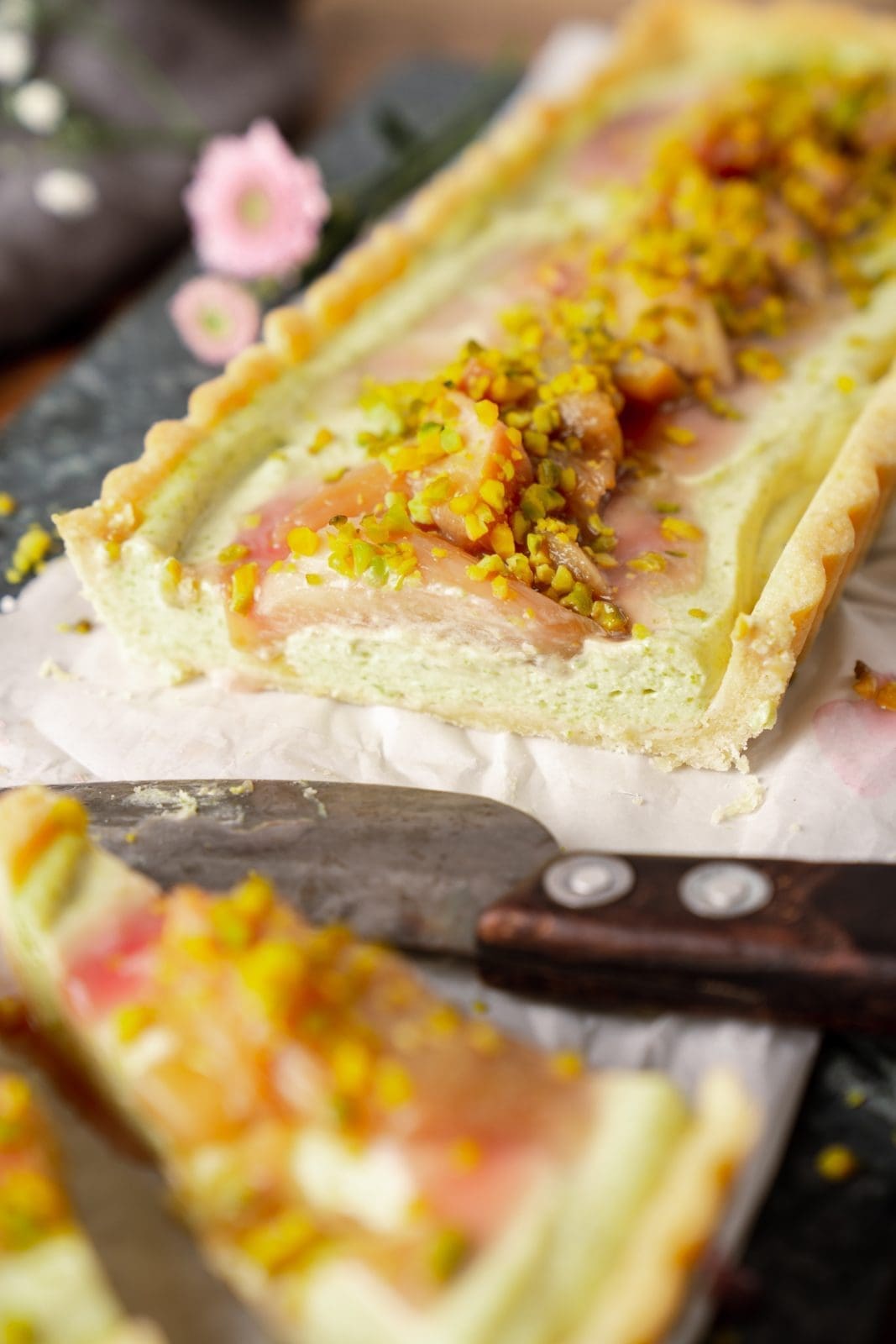 Pistazien-Tarte mit Rhabarber angeschnitten auf dem Tisch in Nahaufnahme