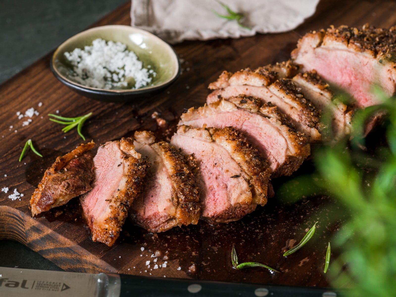 Knusprige Entenbrust aus der Heißluftfritteuse. Komplette Brust aufgeschnitten auf dem Brett und mit Salz bestreut. Rosa glänzendes Brustfleisch.