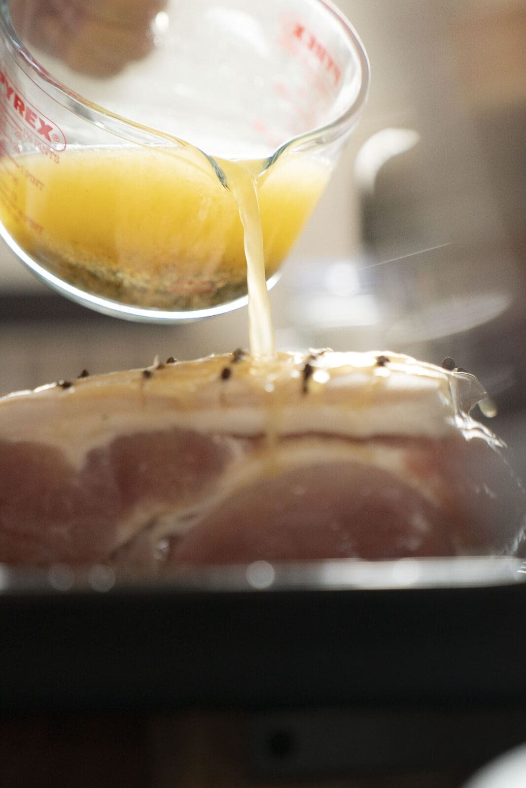 Krustenbraten mit Orangen-Whisky-Glasur 5 Orangensaft wird über Fleisch gegossen.