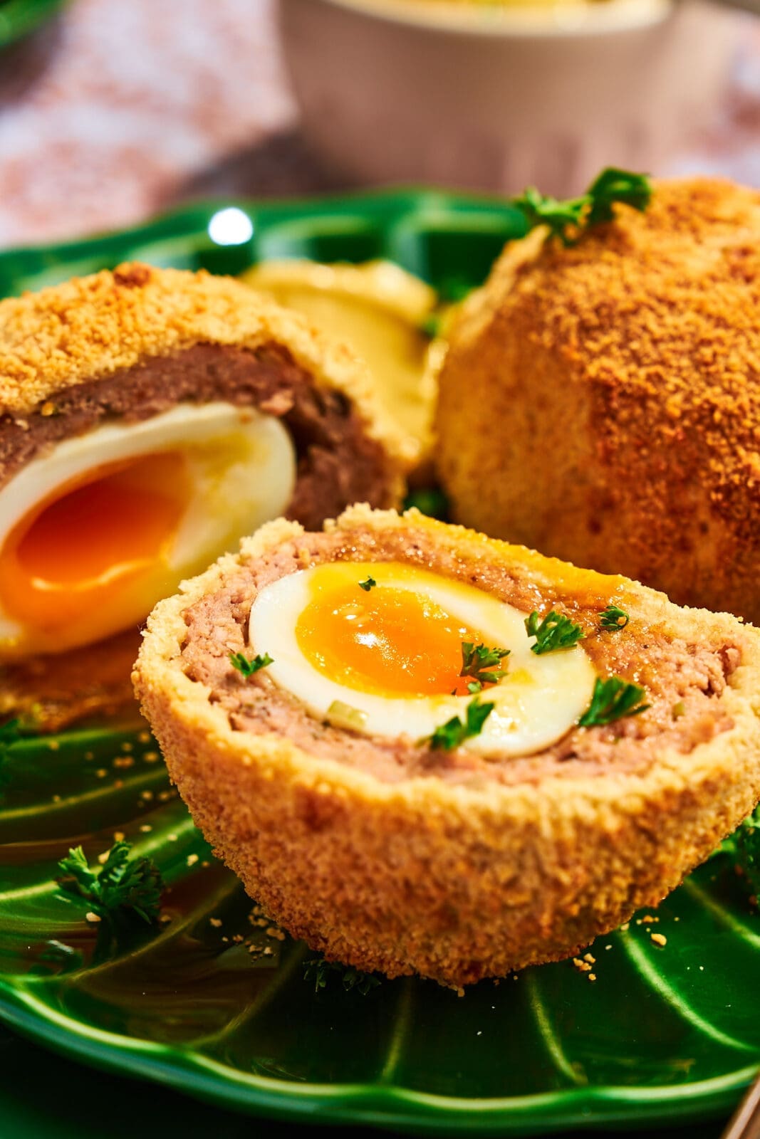 Detailansicht eines aufgeschnittenen schottischen Eis, garniert mit frischer Petersilie, das die saftige Fleischschicht und das weiche Eigelb zeigt.