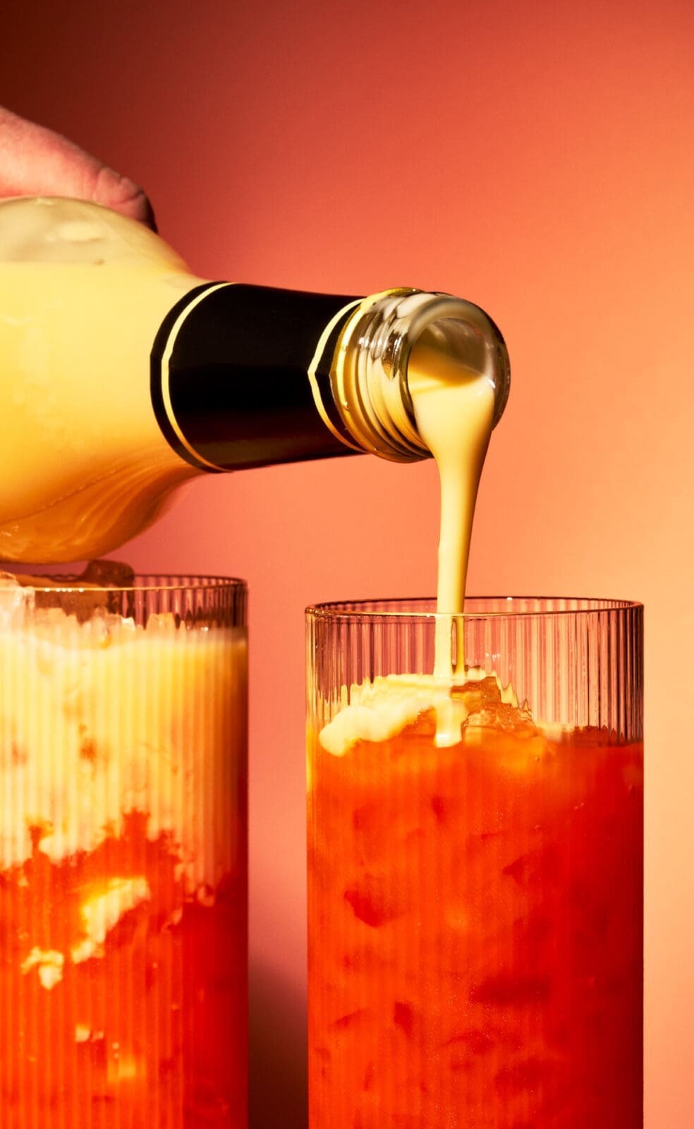 Eierlikör wird vorsichtig über Maracuja- und Karottensaft gegossen, um den Golden Easter Float Cocktail zu schichten.