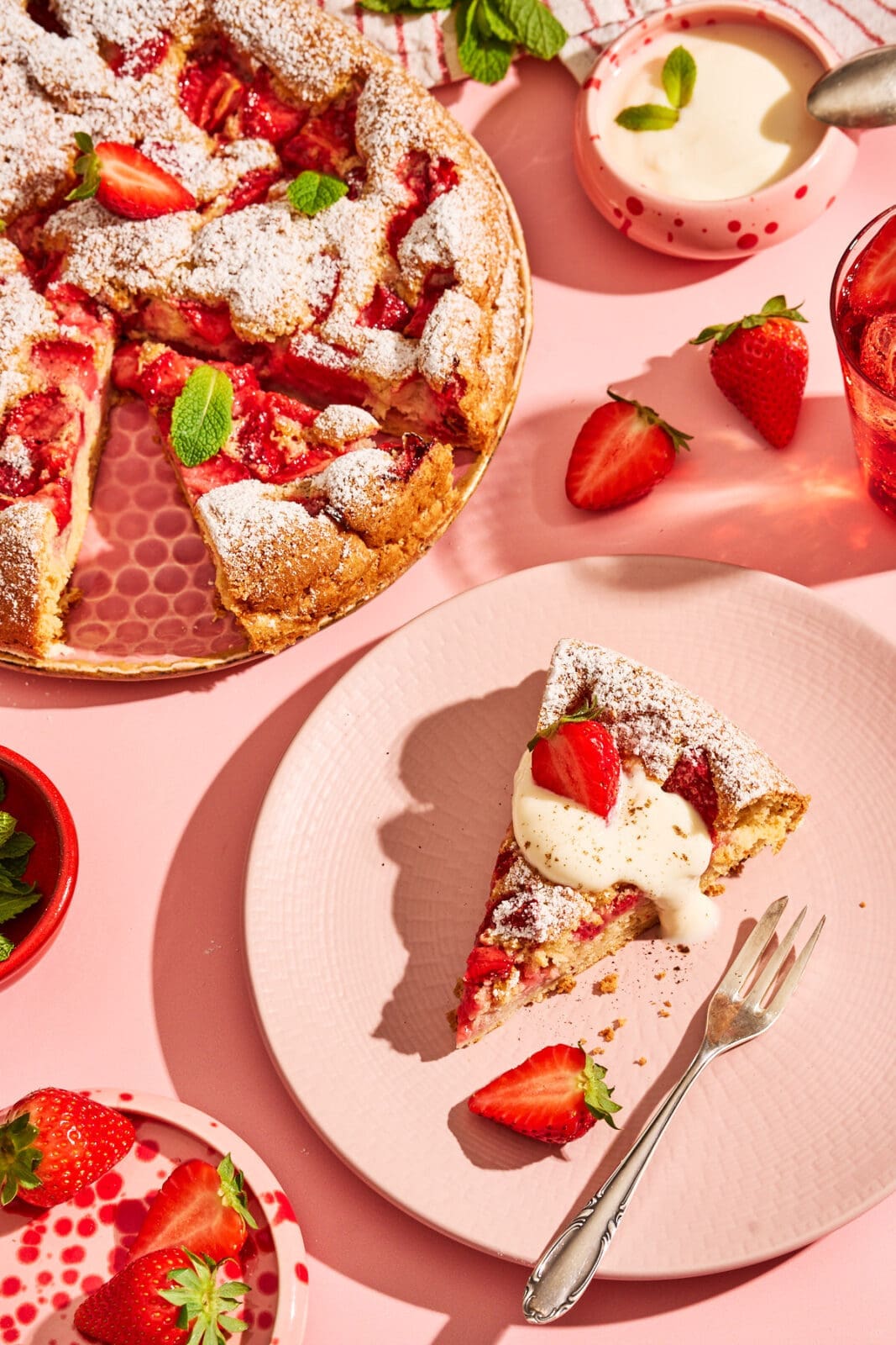 Fluffiger Erdbeerkuchen mit Eischnee-Teig, angeschnitten mit Vanillejoghurt serviert