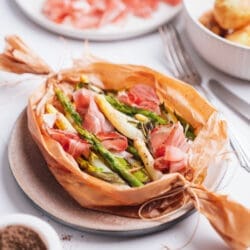 Bunte Spargelpäckchen mit Schinken im Hintergrund