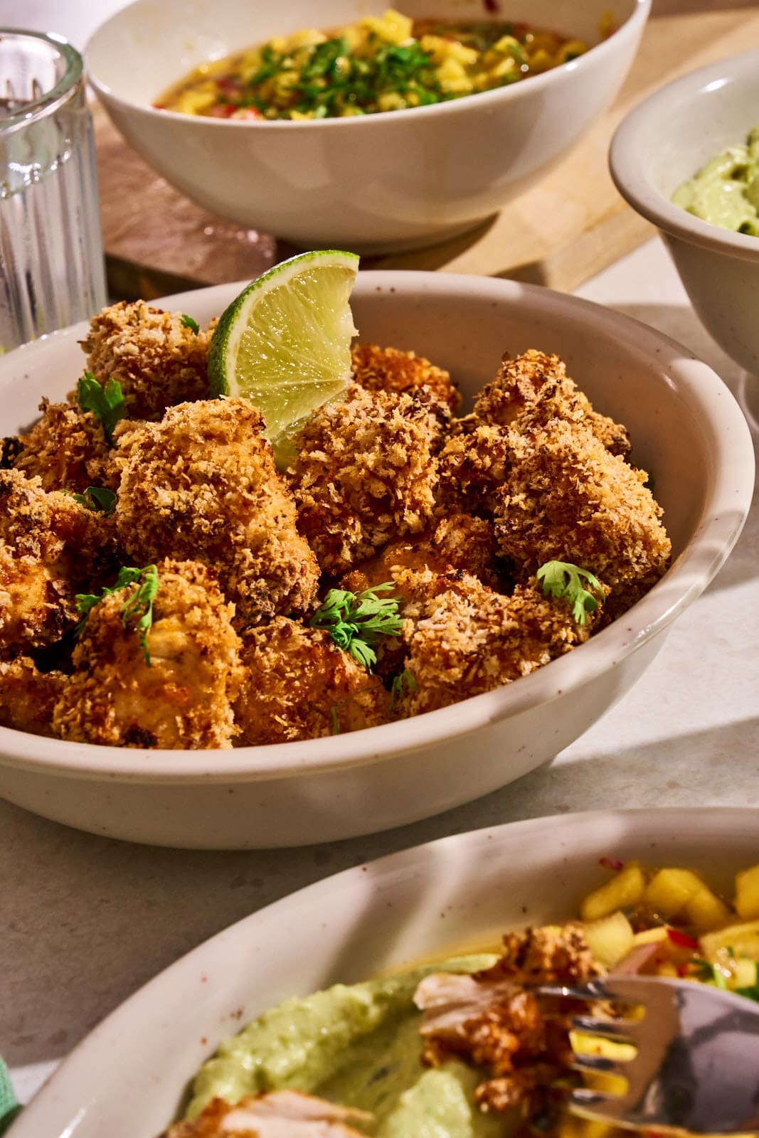 WEB ChickenNuggets Fajita 10 | Chili-Lime Chicken Nuggets aus dem Airfryer. Wenn bei uns Freunde zum Spieleabend oder einfach auf ein Glas Wein vorbeikommen, dann steht immer irgendetwas Leckeres auf einer Platte auf dem Tisch. Für den nächsten Freunde-Abend haben wir dieses Rezept entwickelt und dabei so oft probiert, dass am Ende klar war, dass wir das nicht nur für uns behalten dürfen. Ihr müsst es genauso kennen lernen. Die Kombination aus knusprig paniertem Hähnchen, fruchtig-scharfer Mango-Mandarinen-Salsa und cremigem Avocado-Dip trifft absolut unseren Geschmack.